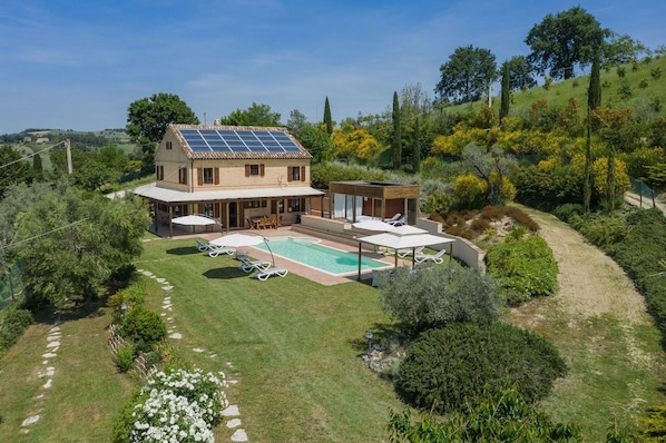 Una casa con piscina, terraza techada y paneles solares.