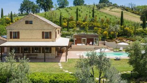 Una casa de dos pisos con piscina, zona de estar al aire libre y jardín.