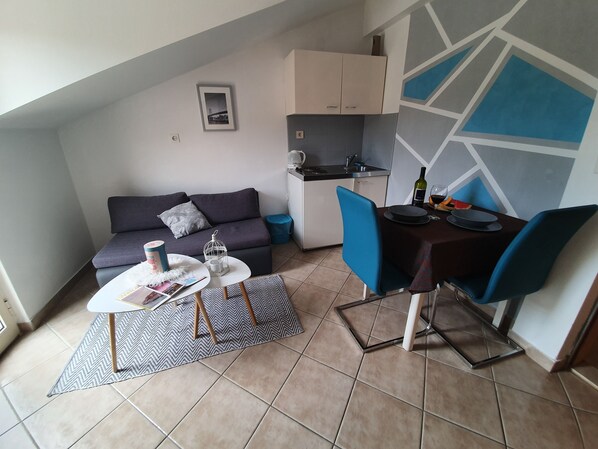 Un espace de vie compact comprenant un canapé, une table à manger et une kitchenette.