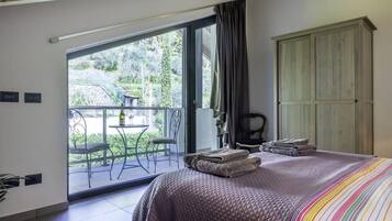 Una camera da letto con un letto grande, un balcone con tavolo e sedie, e un armadio.