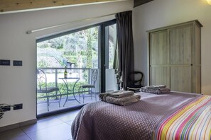 Ein Schlafzimmer mit einem großen Bett, einem Balkon mit Tisch und Stühlen sowie einem Kleiderschrank.