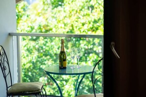 A balcony with a table, a bottle, and two glasses.
