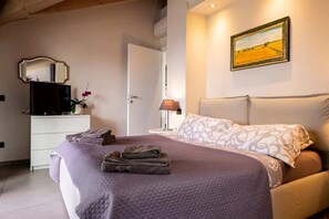 Ein Schlafzimmer mit einem Bett, einem Nachttisch, einer Lampe, einem Spiegel und einem Bild an der Wand.