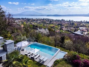 Ein Wohnhaus mit Swimmingpool, Liegestühlen und Blick auf einen See sowie entfernte Berge.