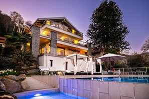 Un hôtel à plusieurs étages doté d’une piscine, d’un espace extérieur aménagé avec des sièges et d’un grand arbre.