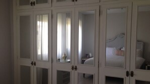 A bedroom with a bed, a nightstand, and a mirror.