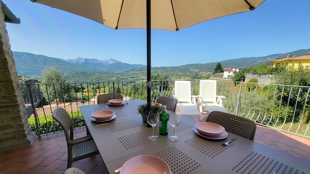 Una terraza con mesa lista para comer, con vistas a un paisaje montañoso.