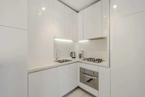 A modern kitchen with white cabinetry, stainless steel appliances, and under-cabinet lighting.