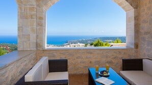 A stone-walled balcony with a view of the sea, two wicker chairs, a table with a glass of beer and a plate of fruit, and a book. - Only 10'min from Rethymno city (Rethymno)
