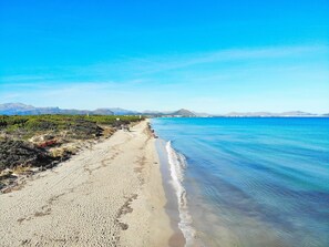 A beach with clear blue water, a sandy shore, and distant mountains. - Sa Costa 411 rustic finca with private pool, terrace, garden and air conditioning (Campos)