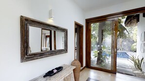 A hallway with a large mirror, a bench, and a door leading to a pool area.