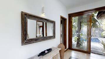 Un couloir avec un grand miroir, un banc et une porte donnant sur un espace piscine.