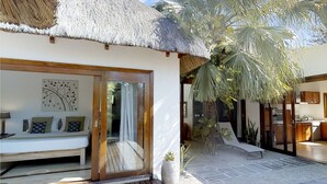 A thatched-roof building with a wooden bench and a wall-mounted artwork.
