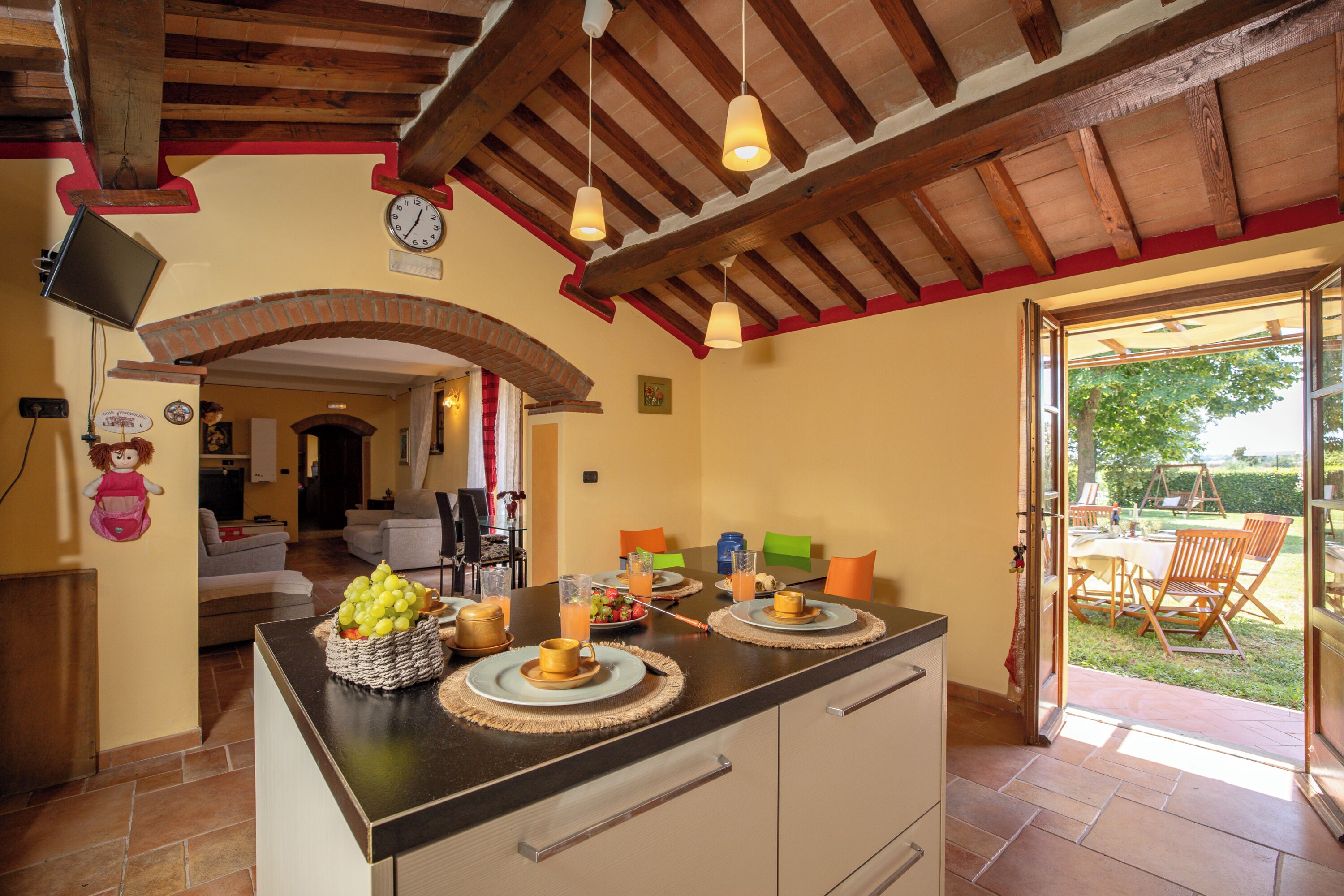 A kitchen with a central island, a dining area with a table and chairs, and an open doorway to an outdoor patio.
