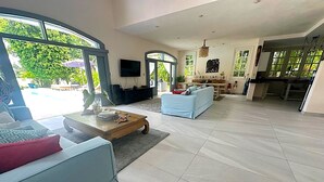 A spacious living room with a large window, a television, and a kitchen area.