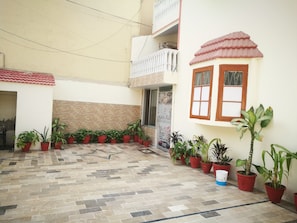 Stroll through the serene courtyard, surrounded by lush greenery and a beautiful herringbone tile floor.