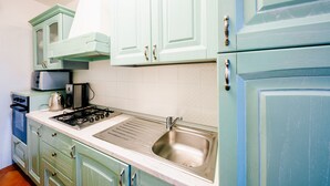 A kitchen with light green cabinets, a stainless steel sink, and a gas stove.