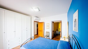 A bedroom with a large bed, a wardrobe, and a door leading to another room.
