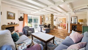 A cozy living room with a fireplace, a stone wall, and a dining area with a view. - Big traditional basque villa with  enclosed garden (Ascain)