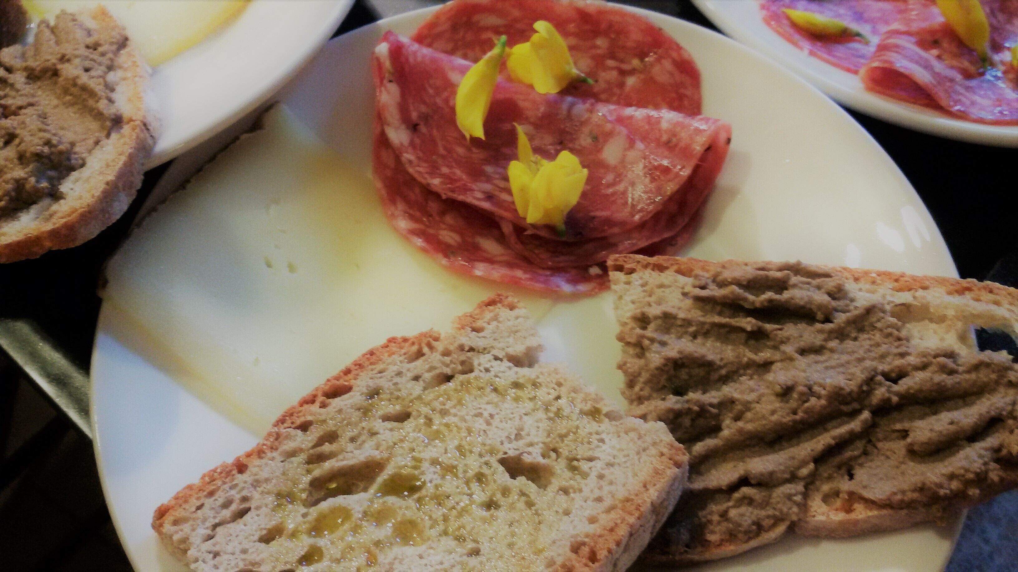 Een bord met sneetjes brood en een stuk vlees, versierd met gele bloemen.