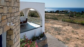 A modern house with a stone exterior, a glass balcony, and a view of the sea. - AELIA LUXURY VILLA IN A PRIVATE ESTATE IN ARDANI KARPATHOS (Amoopi)