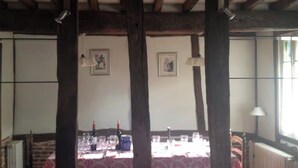 Un coin repas avec une table dressée pour quatre personnes, des poutres en bois et un radiateur.