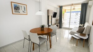 Een eetgedeelte met een ronde tafel, stoelen en een hanglamp.