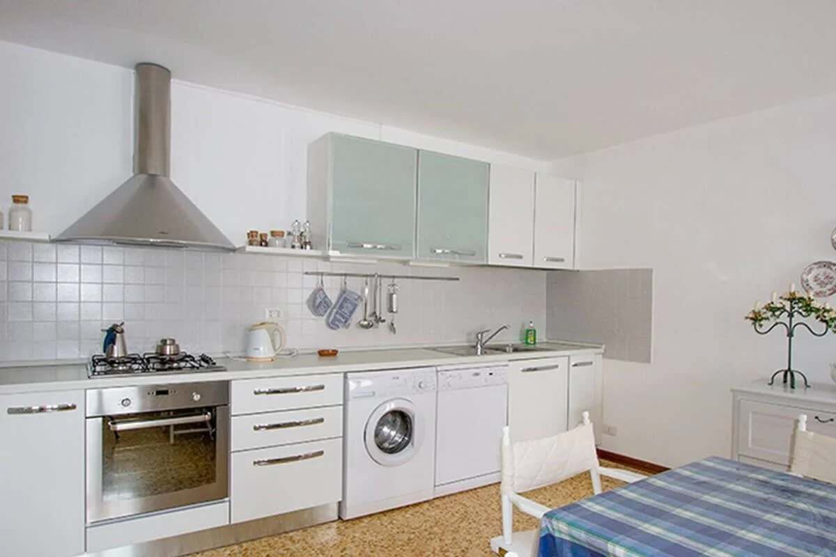 A compact kitchen with a gas stove, oven, washing machine, and a sink.