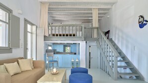 A spacious living area with a high ceiling, a staircase, a kitchen, and a dining area. - Modern Cycladic house with pool (Paros)