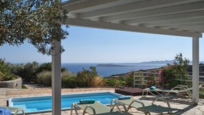 A pool area with lounge chairs and a view of the sea. - Modern Cycladic house with pool (Paros)