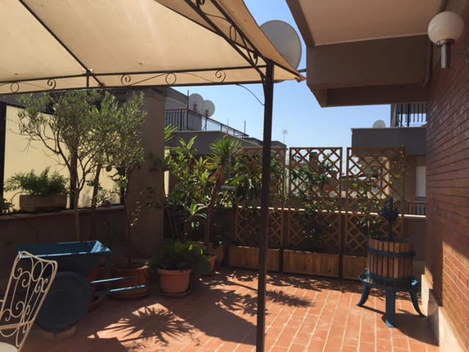 Un espace patio avec un sol en briques, des plantes en pot, une chaise en métal et une table.