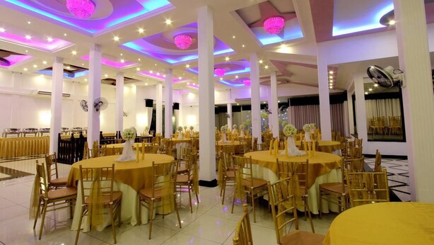 A banquet hall with round tables, golden chairs, and a ceiling with circular light fixtures. - Hotel Mevon (Bandarawela)