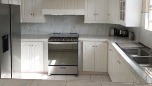 Une cuisine avec des armoires blanches, une cuisinière en acier inoxydable et un évier.