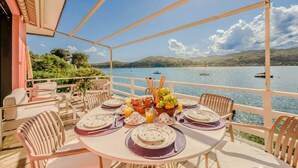 An outdoor dining area with a table set for four, overlooking a body of water with boats. - Italian Lakes lakeside villa with direct lake access (Ranco)