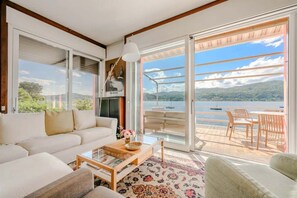 A spacious living area with a sofa, coffee table, and a view of a lake through large sliding glass doors.
