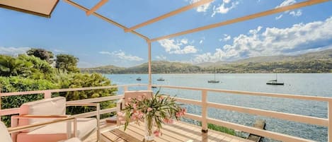 Una terraza con vista a un lago, barcos y colinas.