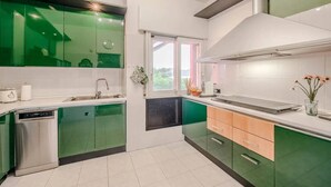 Een moderne keuken met groene kastjes, een vaatwasser en een raam dat voor natuurlijk licht zorgt.