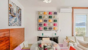 Een moderne woonkamer met een houten hoofdeinde, een glazen salontafel, een bank en een wandlamp.