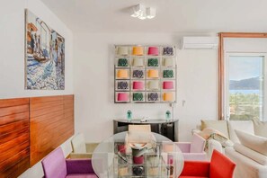 A modern living room with a wooden headboard, a glass coffee table, a sofa, and a wall-mounted lamp. - Italian Lakes lakeside villa with direct lake access (Ranco)