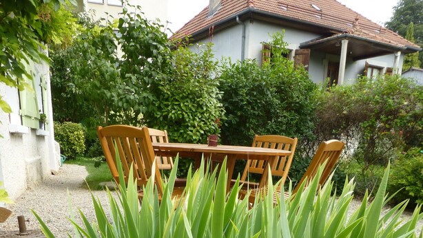 A garden with a wooden table and chairs, surrounded by green plants and hydrangea flowers. - studios - 1 room - 2/4 persons (Annecy)