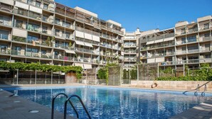 Une piscine avec vue sur un immeuble résidentiel à plusieurs étages.