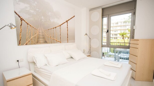 Une chambre à coucher comprenant un lit, des tables de chevet, un bureau, une chaise, une fenêtre avec vue et une œuvre d’art accrochée au mur.