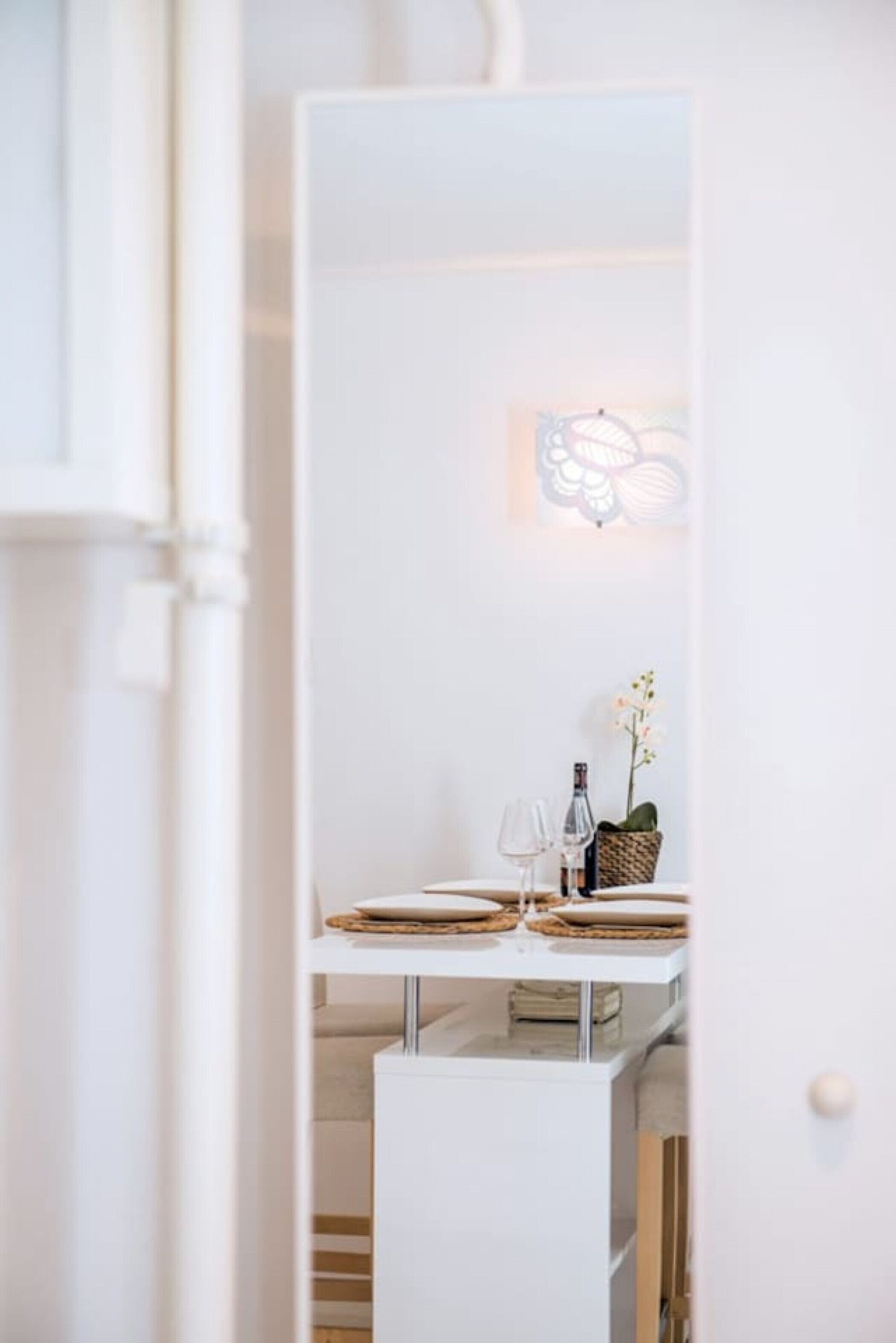 Ein helles Interieur mit einem Essbereich, inklusive Tisch, Geschirr, Gläsern und einer Flasche.