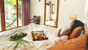 A hotel room with a bed, a tray with breakfast items, a bouquet of flowers, and a view of the outdoors. - Villa Navani - 3 bedroom, 3 ensuite bathroom, private and garden daily cleaning (Pereybere, Grand Baie)