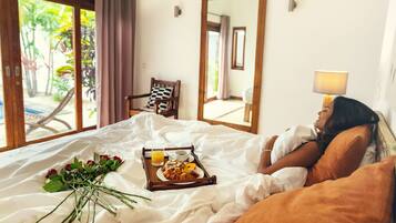 Une chambre d’hôtel avec un lit, un plateau contenant des articles pour le petit-déjeuner, un bouquet de fleurs et une vue sur l’extérieur.