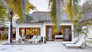 A resort with a pool, lounge chairs, and a thatched-roof building with a bedroom visible through the sliding doors. - Villa Navani - 3 bedroom, 3 ensuite bathroom, private and garden daily cleaning (Pereybere, Grand Baie)