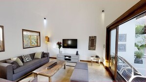 A living room with a sofa, coffee table, TV, and artwork on the walls. - Villa Navani - 3 bedroom, 3 ensuite bathroom, private and garden daily cleaning (Pereybere, Grand Baie)
