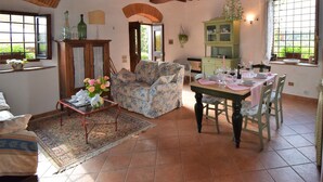 Una sala de estar acogedora con un sofá, una mesa de comedor preparada para cuatro personas y una cocina con un armario y una ventana.