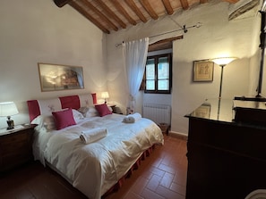 A neatly arranged bedroom with a bed, bedside tables, a dresser, and a window with curtains.