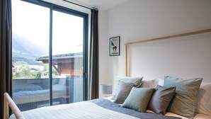 A bedroom with a large bed, a view of a mountain, and a framed picture on the wall. - Spacious Central Apartment with Terrace (Chamonix-Mont-Blanc)